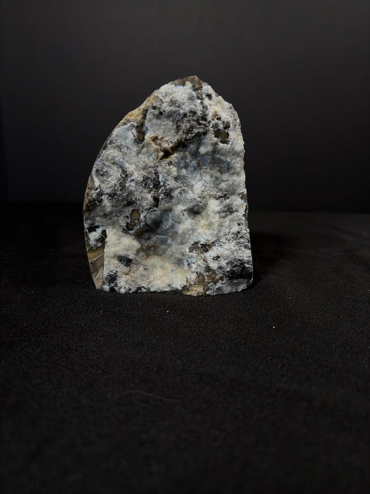 Volcano agate chunk standing upright on a dark surface, showing a natural mix of white, gray, and charcoal tones with druzy crystal pockets and rough mineral textures throughout the stone.